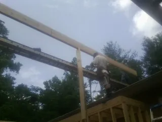 Carpenter setting a ridge beam over a new addition frame — Ice Dam Removal by Roofing Brothers in Enville