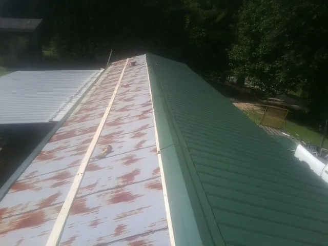 Old rusted panels beside newly installed green metal roofing — Wind Damage Roof Repair by Roofing Brothers in Enville