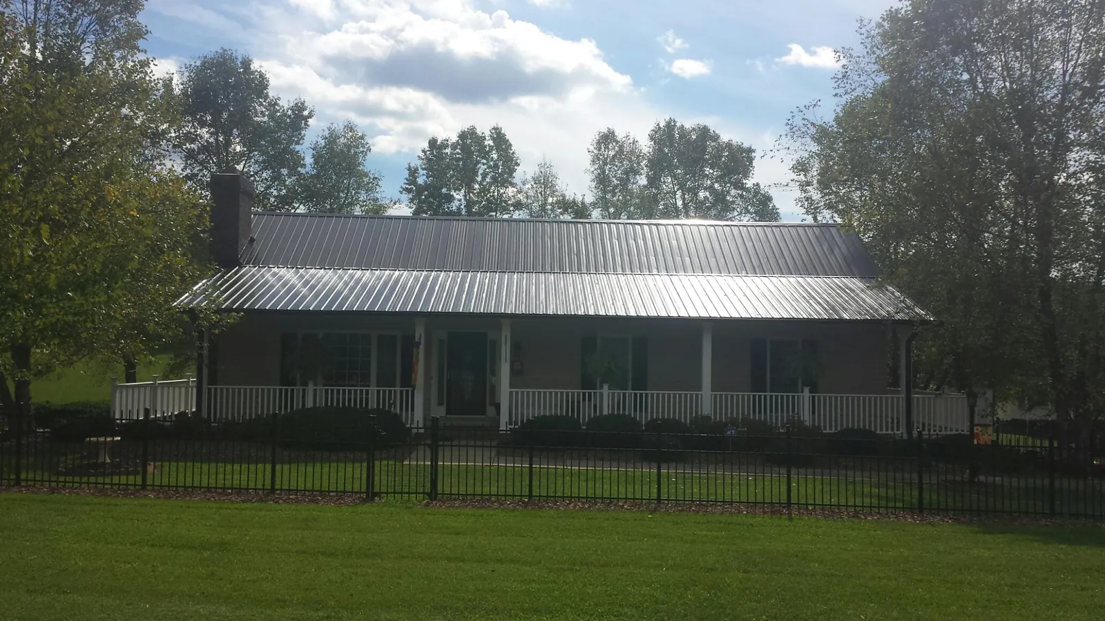 Gray metal roof on a brick ranch with a full width front porch — Gutter Guard Installation work by our crew in Enville