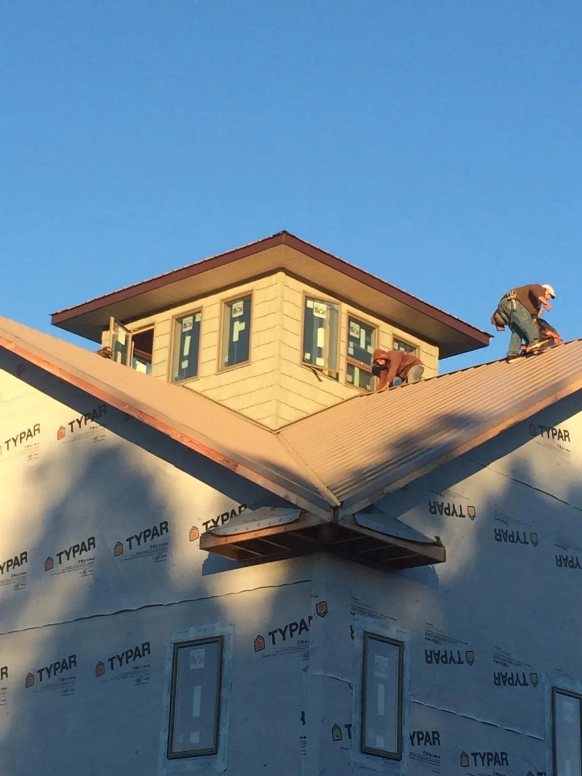 Roofers working around a rooftop cupola on a new metal roof at sunset — Roof Waterproofing in Enville by Roofing Brothers